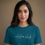 Close-up chest graphic detail of the inhale exhale t-shirt featuring cursive lettering and heart accent